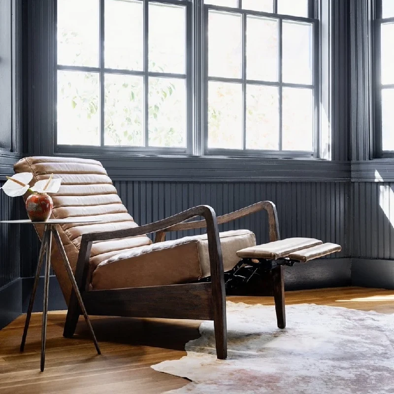 A tan leather upholstery armchair with a reclining footrest in a sunlit room.