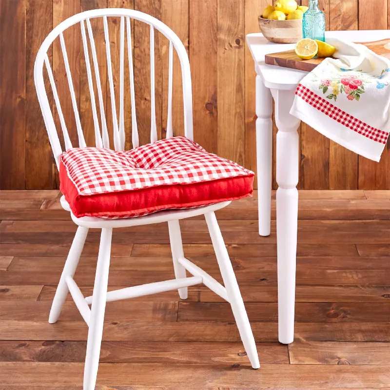 Red and white checkered seat cushion on a white wooden chair.