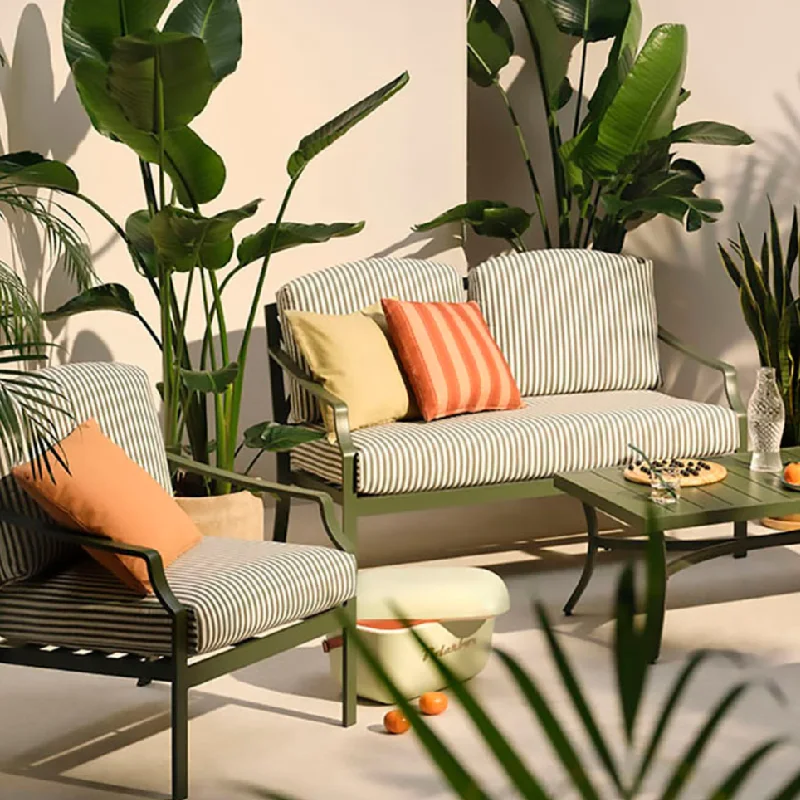 Striped seat cushions on outdoor chairs with solid and striped throw pillows.