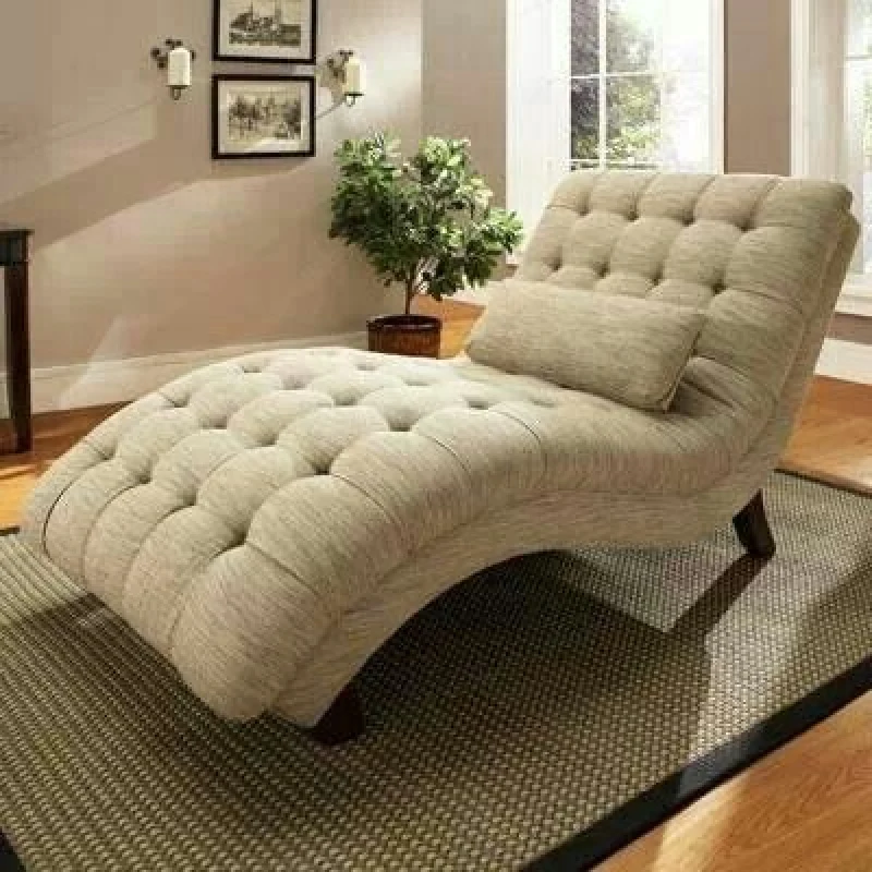 Tufted gray chaise lounge with a bolster pillow.
