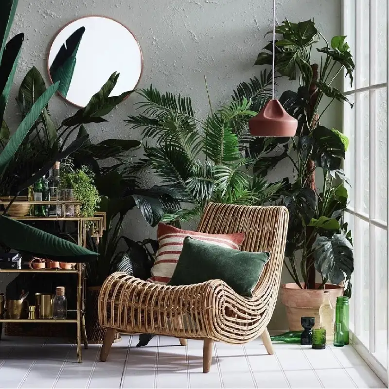 Woven rattan chair with striped and velvet throw pillows.