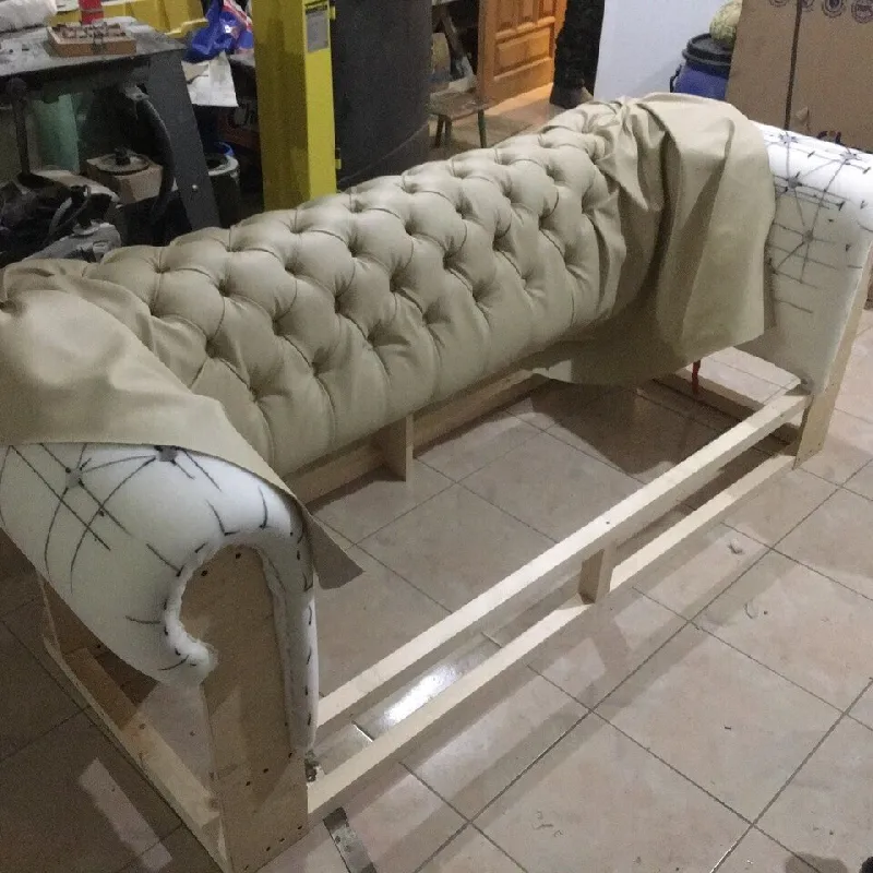beige leather couch being reupholstered, with the new fabric partially draped