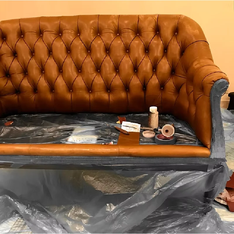 brown leather tufted sofa in the process of being repaired, with various tools
