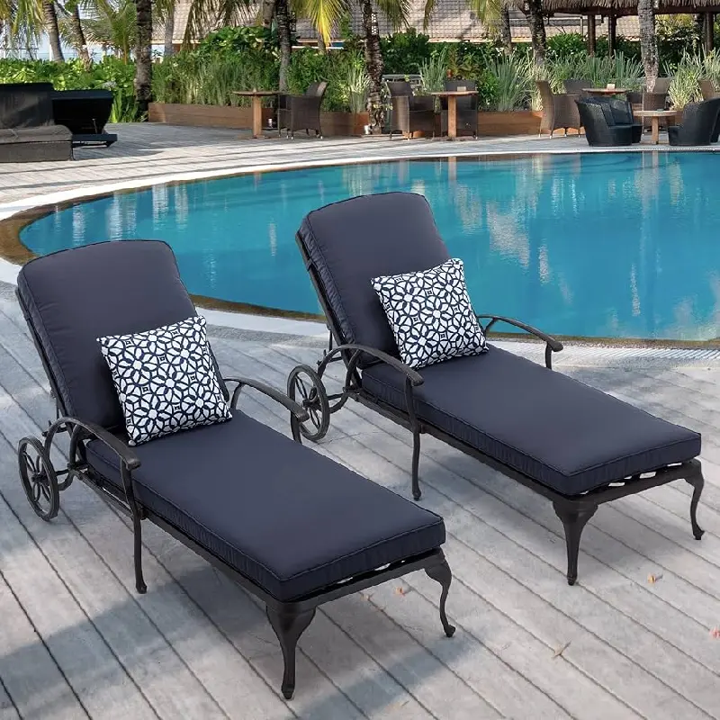 dark outdoor chaise lounges with pillows beside a swimming pool