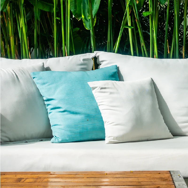 outdoor cushions in white and a single turquoise one sits on a lounge chair