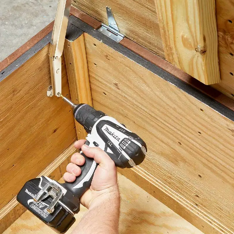 power drill to screw a metal hinge into a wooden frame