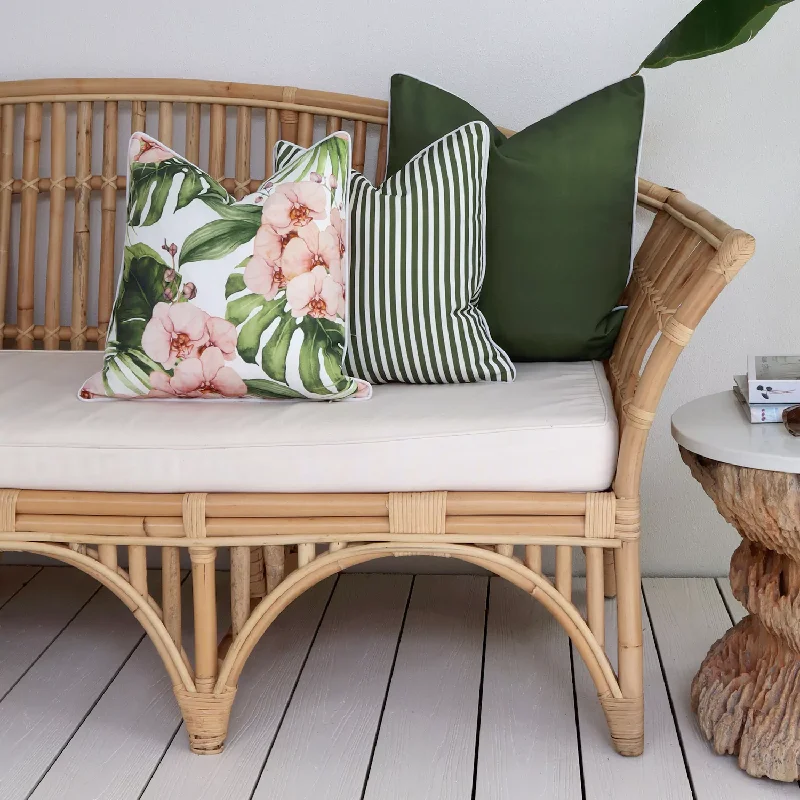 rattan bench features a cream-colored outdoor cushion and is decorated with three throw pillows