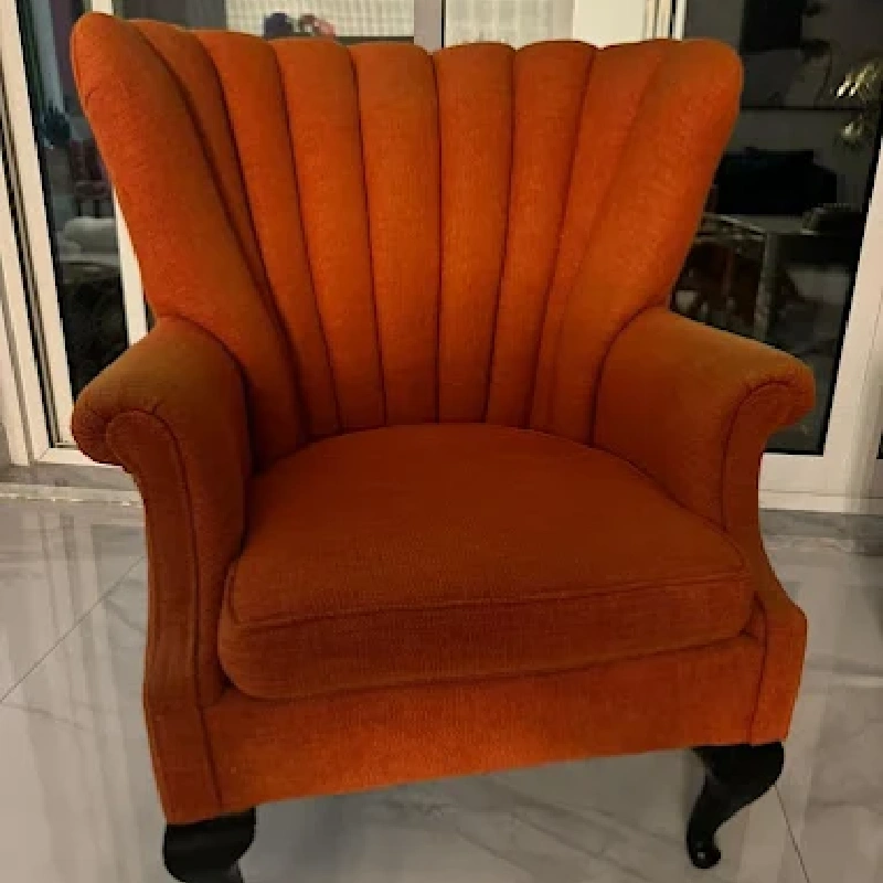vintage-style armchair with vibrant orange fabric upholstery and vertical channel tufting on the back