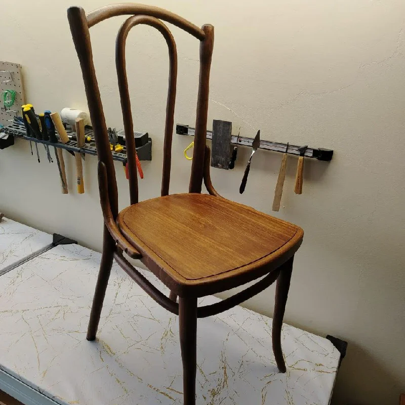 wooden chair with a curved back and seat is being repaired in a workshop