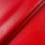 Close up folded smooth red faux leather upholstery fabric