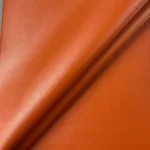 Close up macro texture shot of orange vinyl leather fabric