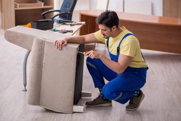 Furniture repairman assembling a beige fabric armchair